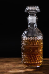 Whiskey decanter on wooden table on black background. Alcohol concept