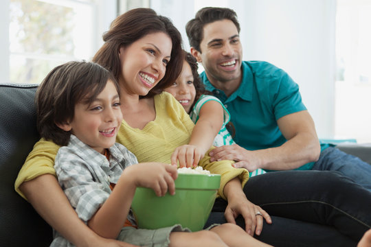 young family of four sharing popcorn on movie night