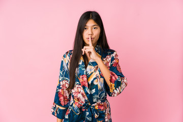Young asian woman wearing a kimono pajamas keeping a secret or asking for silence.