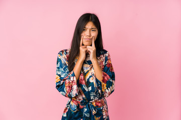 Young asian woman wearing a kimono pajamas doubting between two options.