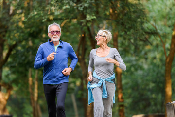 Cheerful active senior couple jogging in the park. Exercise together to stop aging.