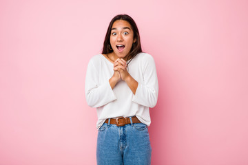 Young mixed race indian woman praying for luck, amazed and opening mouth looking to front.