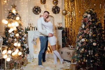 Photo of charming, attractive, cute, elegant, gorgeous lady hug handsome man in formal wear stand in room near Christmas tree. Pair hugging her boyfriend for Valentine's Day.