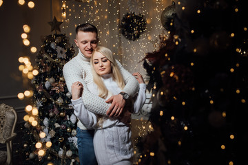 Beautiful couple of young lovers in Christmas interior. Sweet couple Love smile  and celebrating new year eve, birthday, and valentine on decoration in living room at home. 