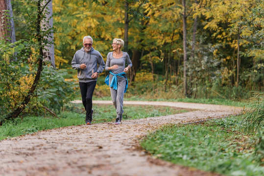 Cheerful active senior couple jogging in the park. Exercise together to stop aging.