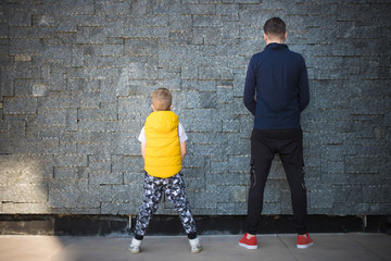 Back view of father and son against the wall.