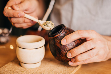 Men's hands prepare a portion of hot invigorating mate