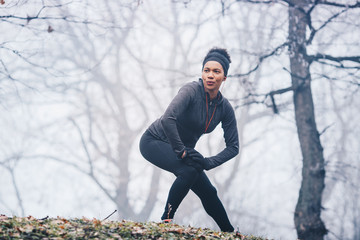 Fototapeta premium A woman warming up for exercise on a misty morning in nature.