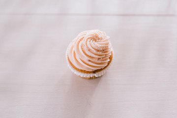 Cupcake with pink icing and pearl sprinkles on white bench