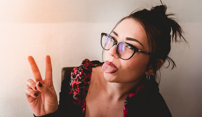 Portrait of young woman making funny face in front of camera - Concept of millennial girl taking...