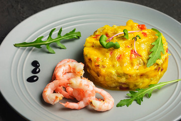 On a black background, a gray plate with an Asian national recipe. Mango chutney with pepper and shrimp.