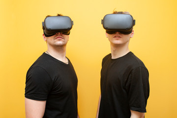 two guys in VR glasses on a yellow background, a pair of serious friends of gamers in virtual reality glasses
