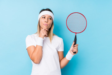 Young caucasian woman playing badminton isolated looking sideways with doubtful and skeptical expression.