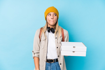 Young caucasian woman holding pizzas isolated confused, feels doubtful and unsure.