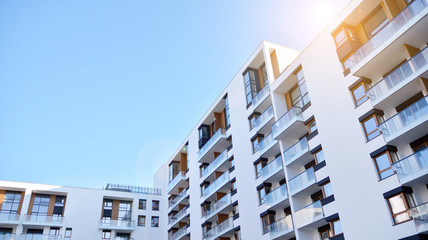 Modern multi story building being lit by the setting sun at afternoon. New apartment house residential building outdoor concept.