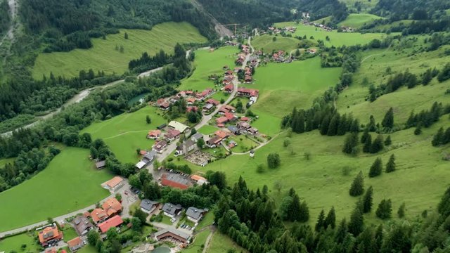 Scenic Aerial View of Mountain Village in Alpine Countryside. Agriculture and Ecotourism in Bavaria, Germany. 4K Drone Fly over Shot