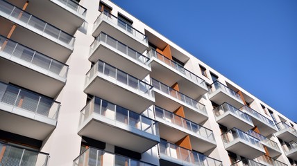 Modern multi story building being lit by the setting sun at afternoon. New apartment house residential building outdoor concept.