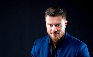 Obraz premium Attractive young guy posing in studio. Portrait of a handsome man with light beard and nice face. Confident look to the camera. Horizontal portrait