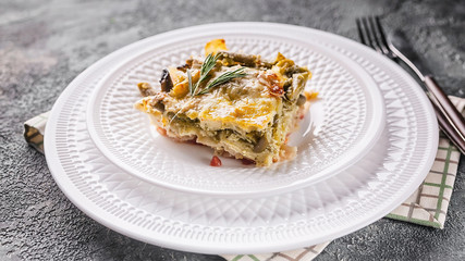 Close up baked vegetable lasagna with green beans and cheese on a white plate. Delicious vegetarian food.