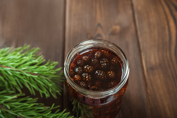 Traditional Trend Siberian dessert - young pine cones jam. Ukrainian cone jam in a jar on a dark background close-up and copy space.