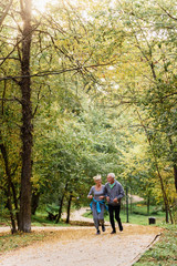 Cheerful active senior couple jogging in the park. Exercise together to stop aging.