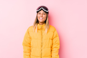 Young caucasian woman wearing a ski clothes in a pink background happy, smiling and cheerful.