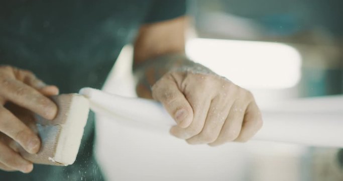 Surfboard shaper sanding the nose of a surfboard, skilled craftsman shaping a surfboard with focus and precision