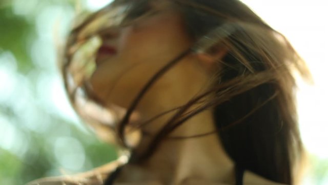 Woman swinging hair in movement sideways. Pretty girl waving hair