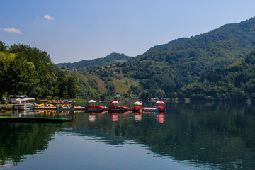 Fototapeta na wymiar calm beautiful lake surrounded by forests and tourist boats. Sights of Bosnia and Herzegovina.