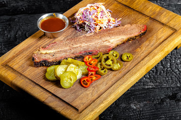 background black burnt carbonized forest, structure, wooden cutting board, meat brisket, pickles...