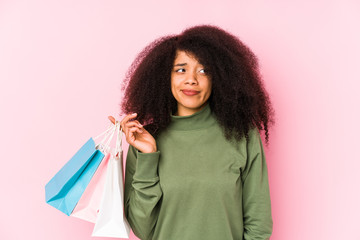 Young afro woman shopping isolated Young afro woman buying isolaYoung afro woman holding a roses isolated confused, feels doubtful and unsure.< mixto >