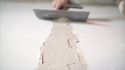 Worker using the trowel for plastering the concrete wall at the construction site. Making the smoothness and flat the surface of cement wall by wooden trowel. Labor day. 