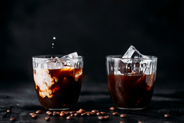 Pouring milk into a glass of espresso coffee with ice