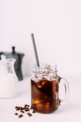 Iced coffee drink on glass jar with straw.