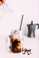 Iced coffee drink on glass jar with straw.