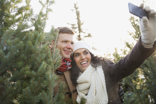 Couple taking self portrait while shopping for Christmas tree