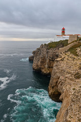 Fototapeta na wymiar Beautiful rocky coastline landscape with lighthouse on Sao Vincente cape. Farol doCabo de Sao Vicente, Algarve, Portugal. 