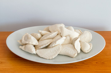 Raw frozen dumplings on white plate.