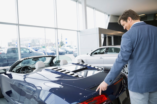 Man looking at convertible in car dealership showroom