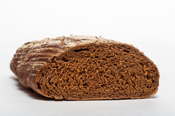Sliced loaf of black rye bread with cuts from a knife on top of it and sprinkled with white flour isolated on a white background. Healthy eating concept. Close-up side view of bread.