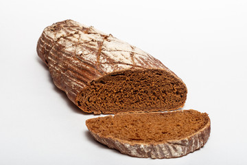 Sliced loaf of black rye bread with cuts from a knife on top of it and sprinkled with white flour isolated on a white background. Healthy eating concept.