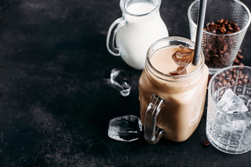 Cold iced coffee with ingredients: ice cubes, milk, coffee beans