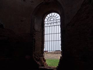 Fototapeta na wymiar Alone window with bars in a dark old building overlooking the field