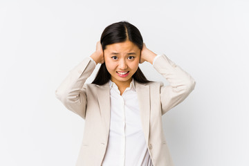 Young chinese business woman isolated covering ears with hands trying not to hear too loud sound.