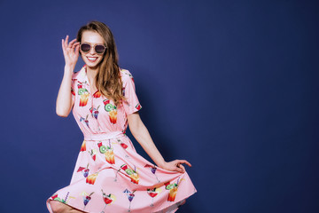 Girl in floral dress emotionally poses on the blue background.