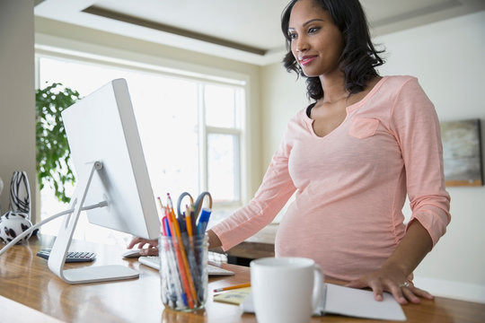 Pregnant woman using computer at home