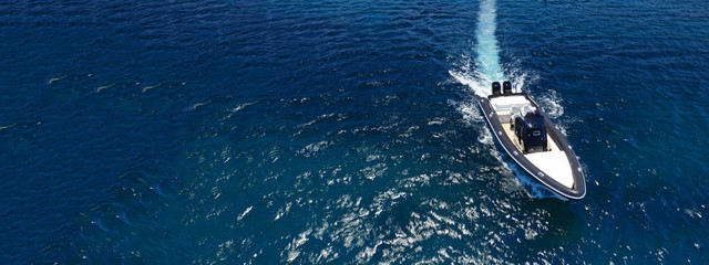 Aerial drone ultra wide top down photo of luxury rib inflatable with wooden deck cruising in deep blue open ocean sea