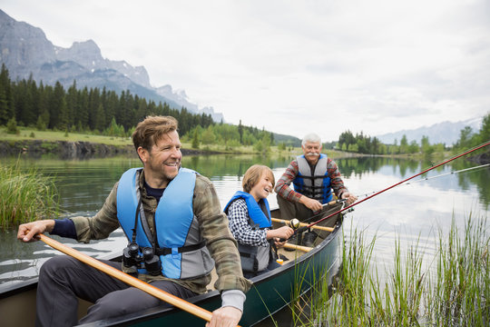 Three Generations Of Men Fishing In Lake