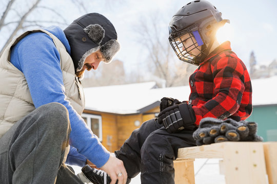 Father tying ice-skates for son