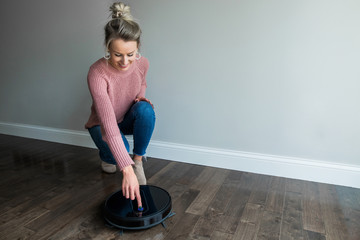 A Young woman starting her robotic vacuum